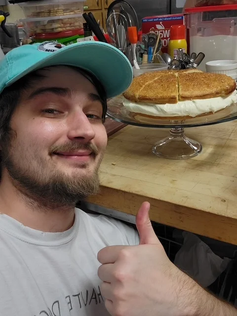 Homemade cheesecake with a golden crust on a glass cake stand