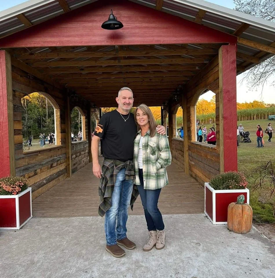 Couple posing in a rustic outdoor setting with wooden architecture