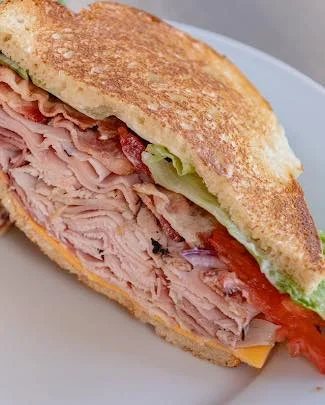A hearty sandwich loaded with layers of turkey, cheese, lettuce, and tomatoes on toasted bread.