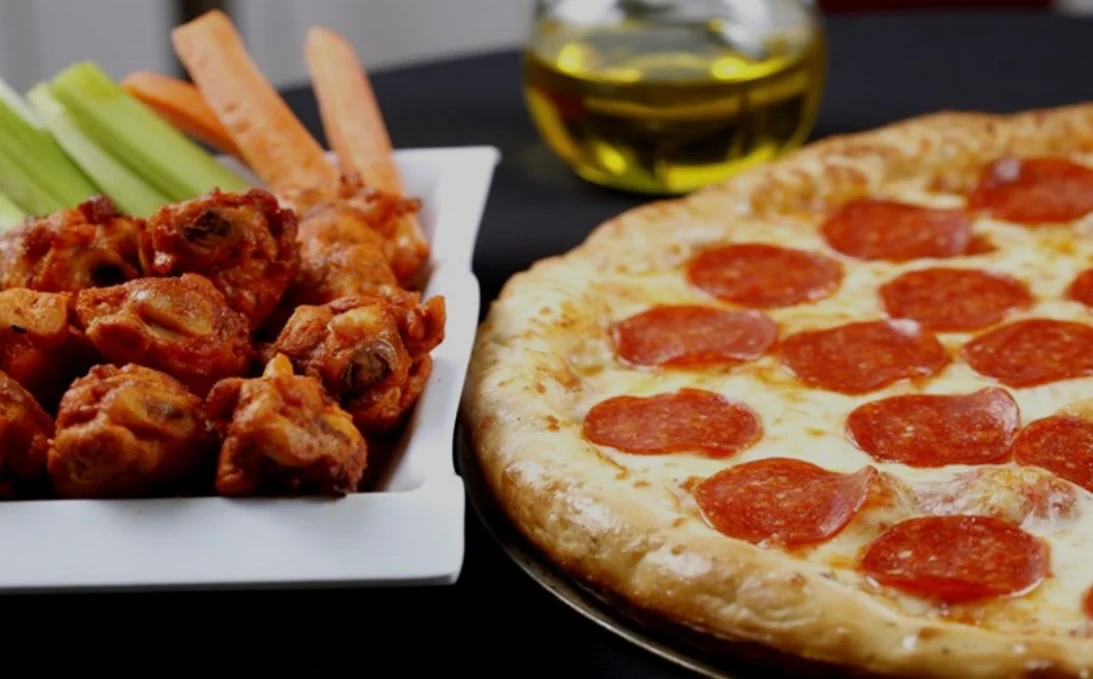 Classic pepperoni pizza with buffalo chicken wings and celery sticks