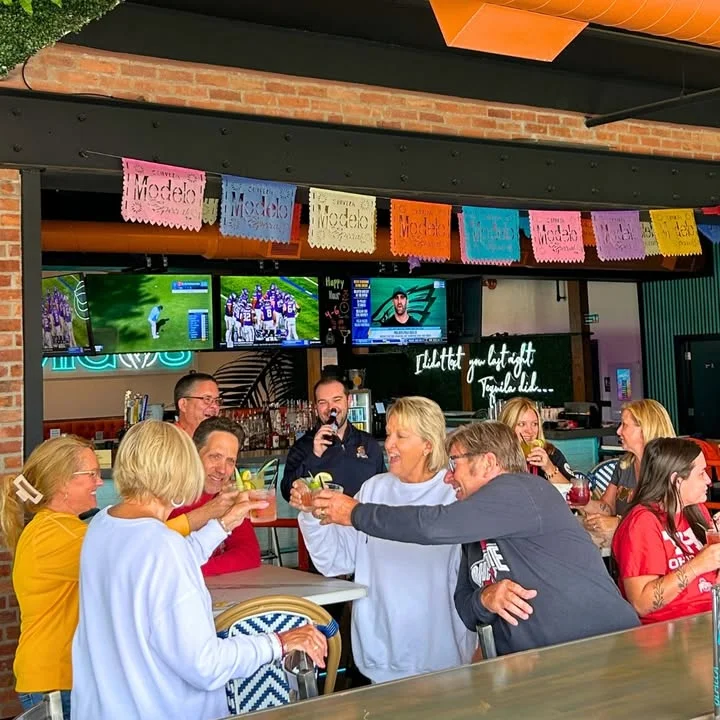 Group of friends toasting with cocktails in a vibrant bar setting