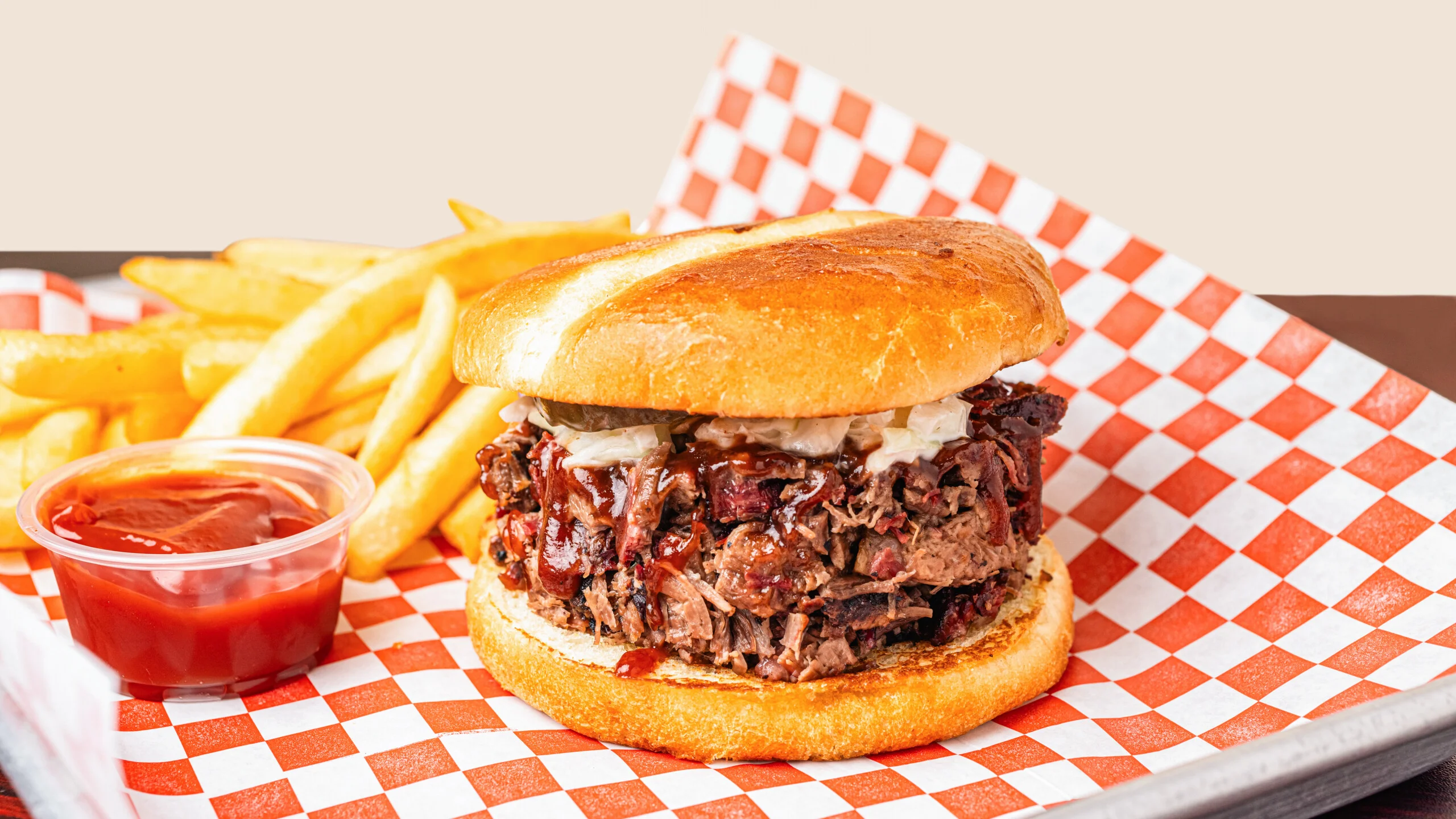 BBQ brisket sandwich served with fries and ketchup on a checkered tray