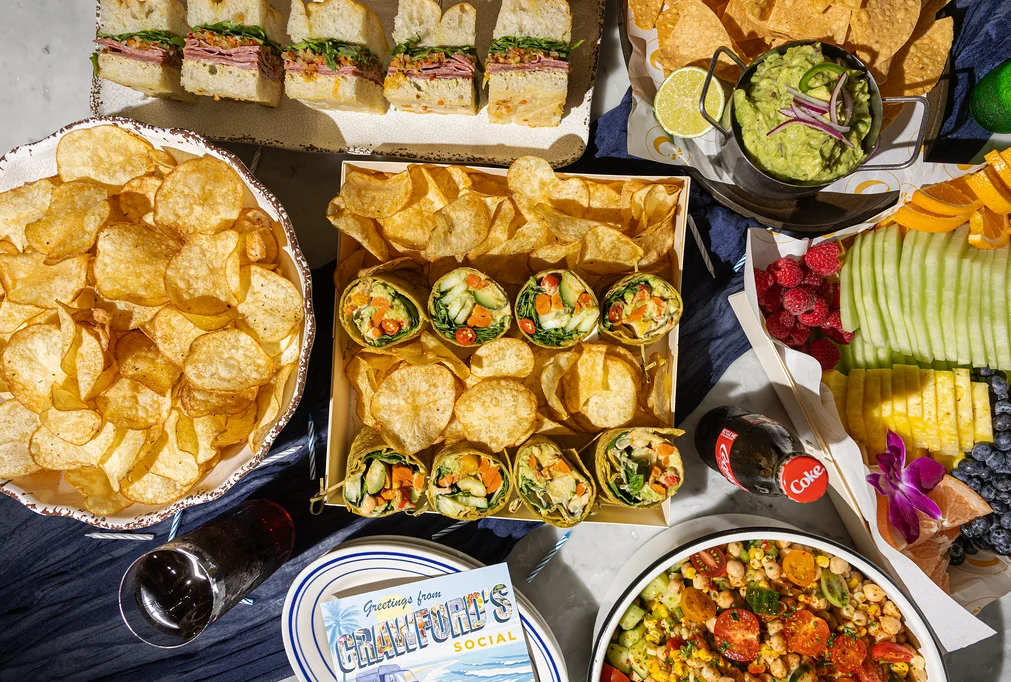 Assorted party platters with wraps, chips, and fresh fruit