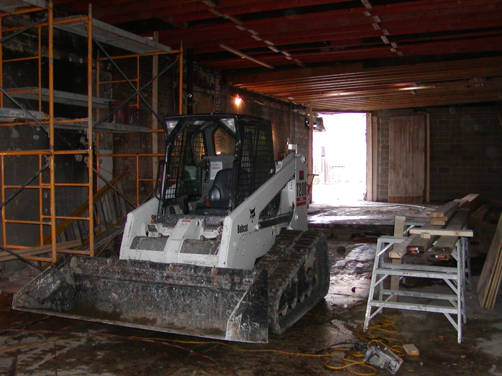 Construction site with a Bobcat loader and scaffolding in a renovated space