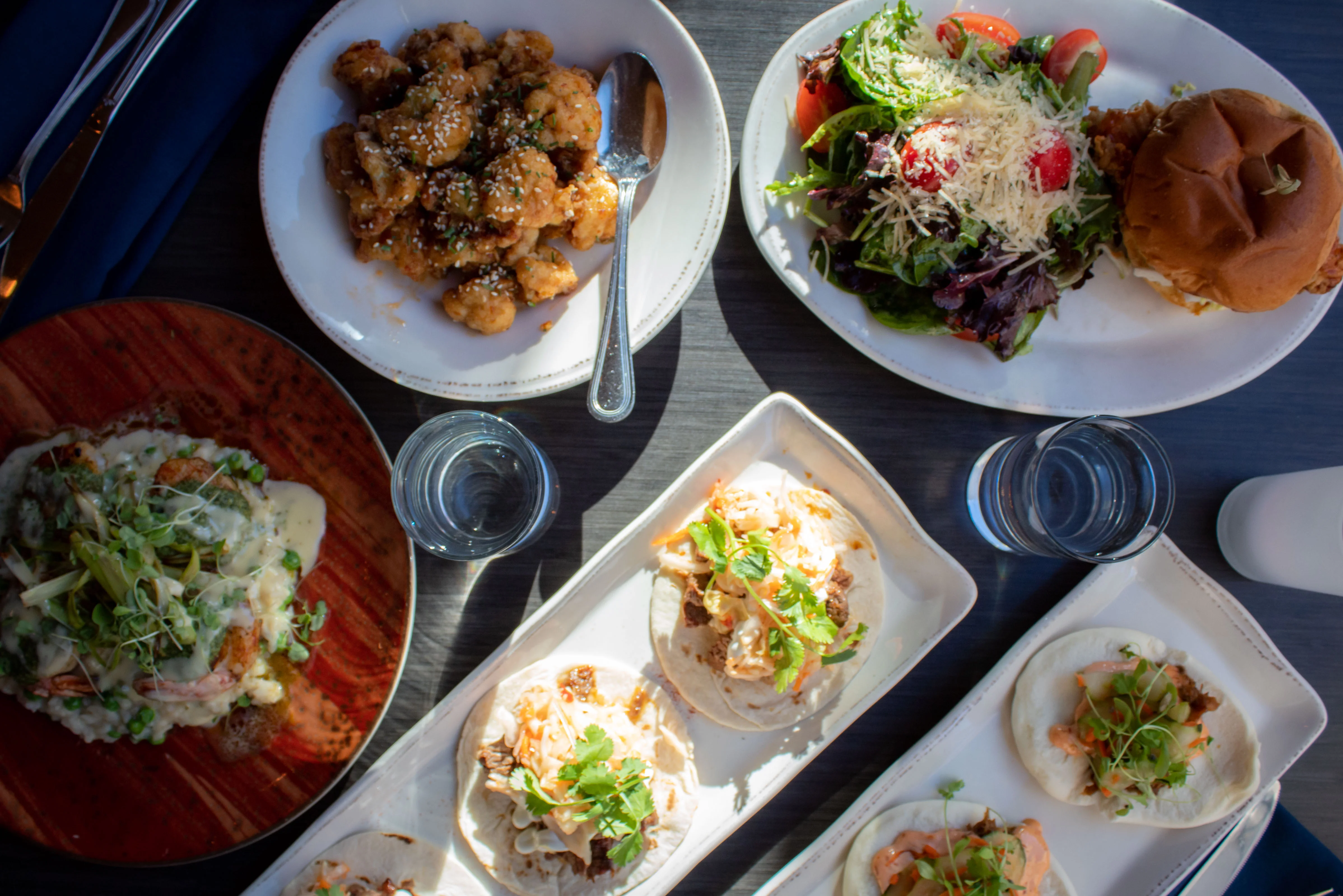 Assorted dishes including tacos and salad in a vibrant restaurant setting