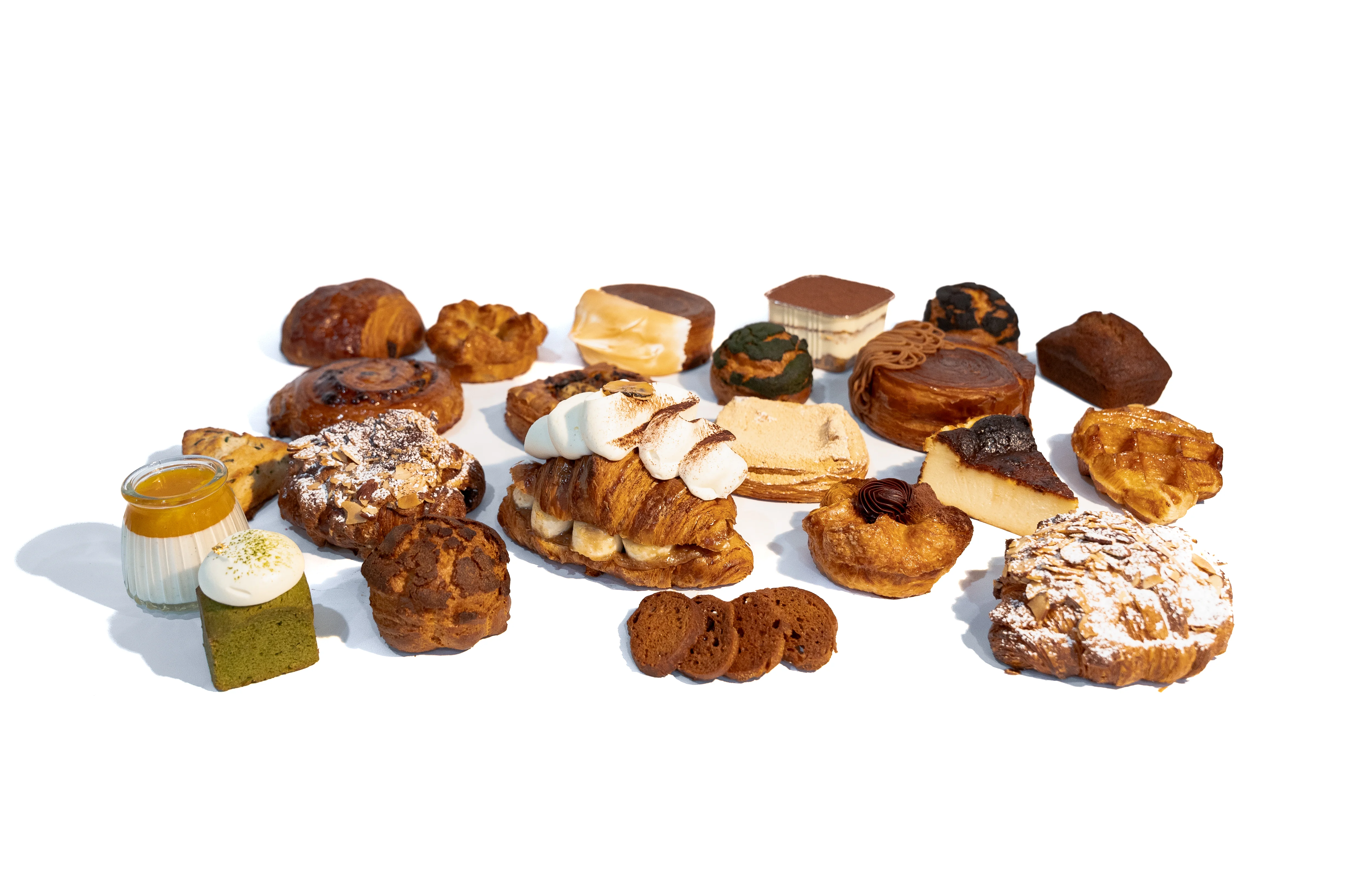 An assortment of various pastries and desserts, including croissants, cakes, and sweets, beautifully arranged on a white background.