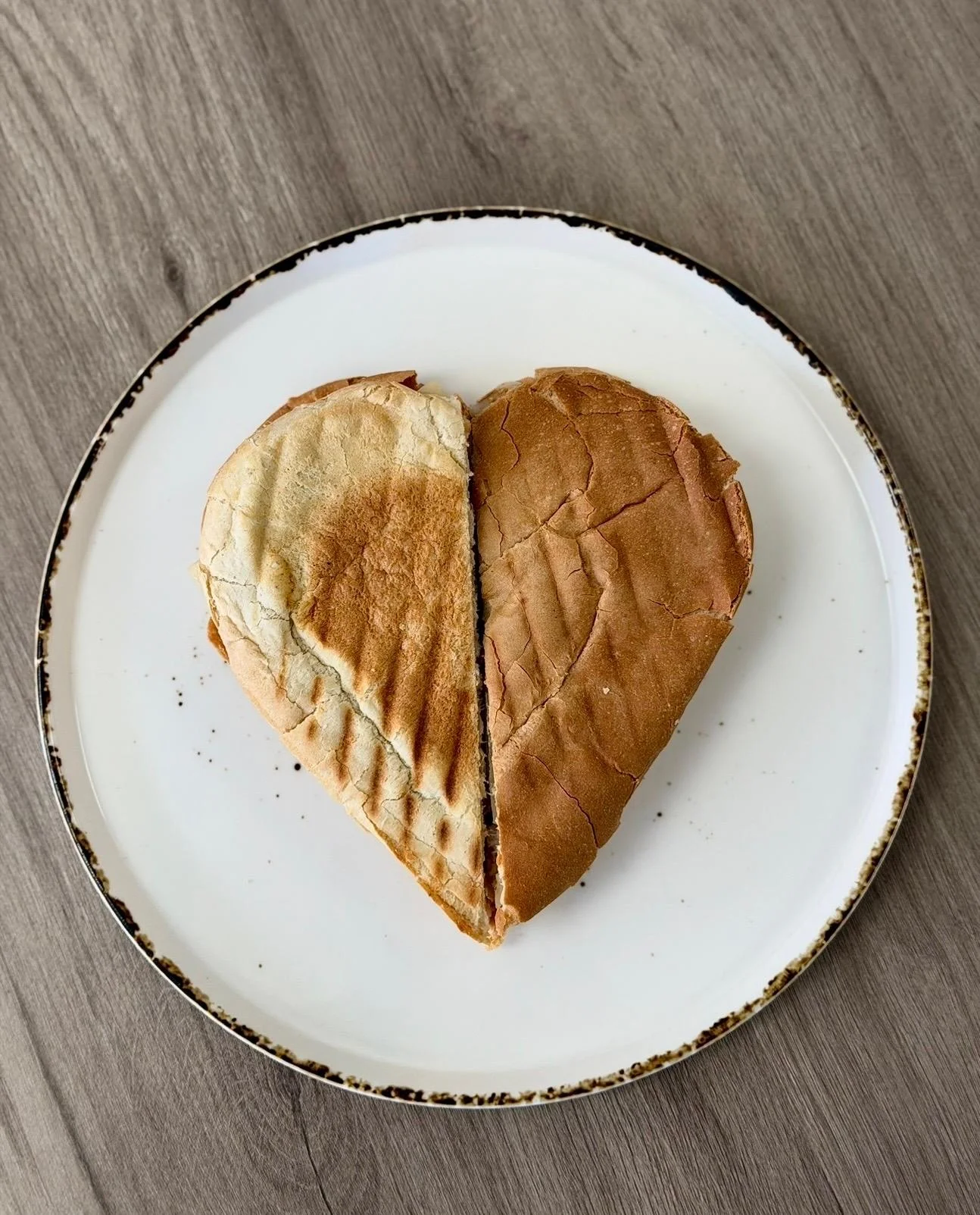 A heart-shaped bread loaf, beautifully baked and presented on a plate.