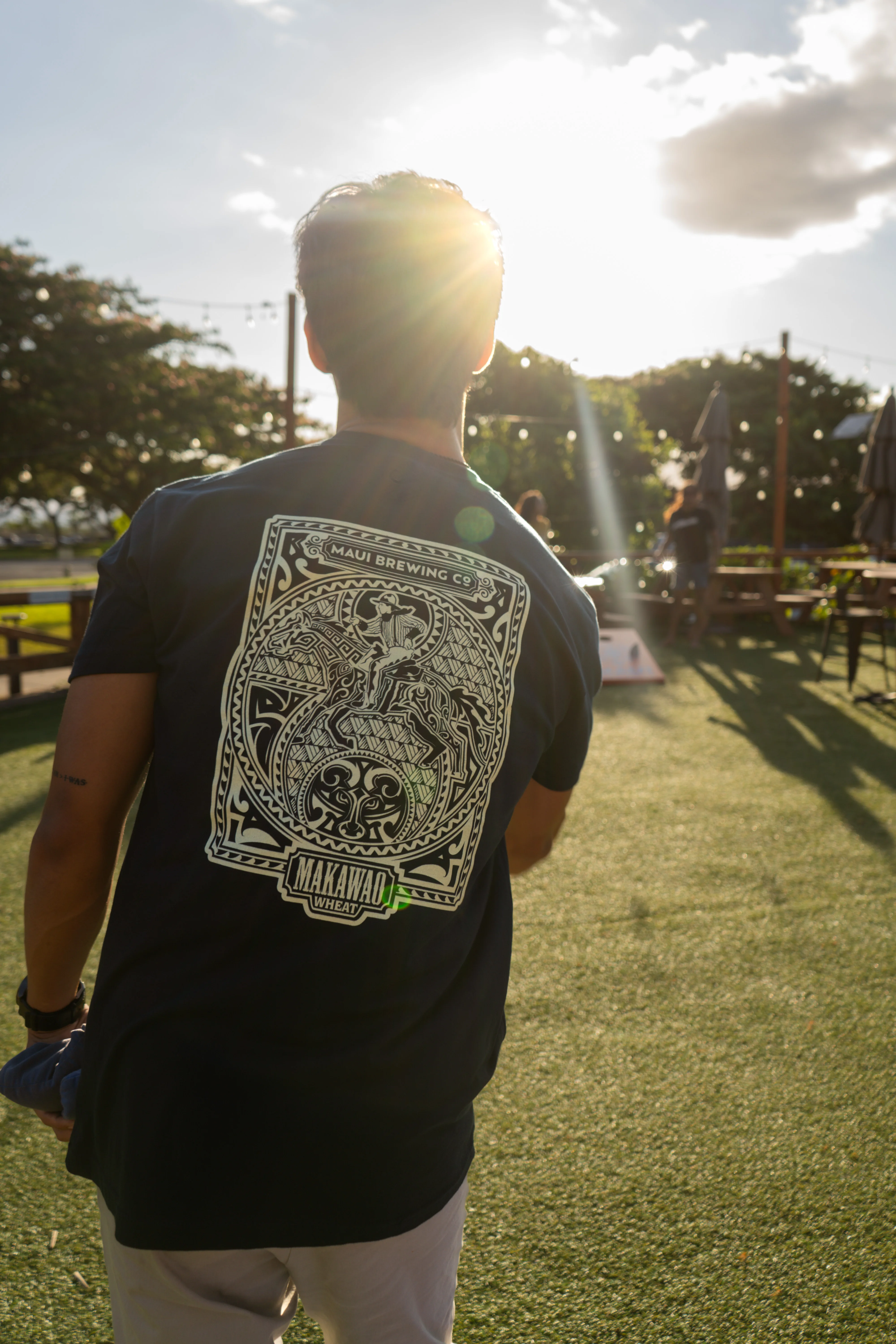Person wearing Maui Brewing Co. shirt in a sunny outdoor setting