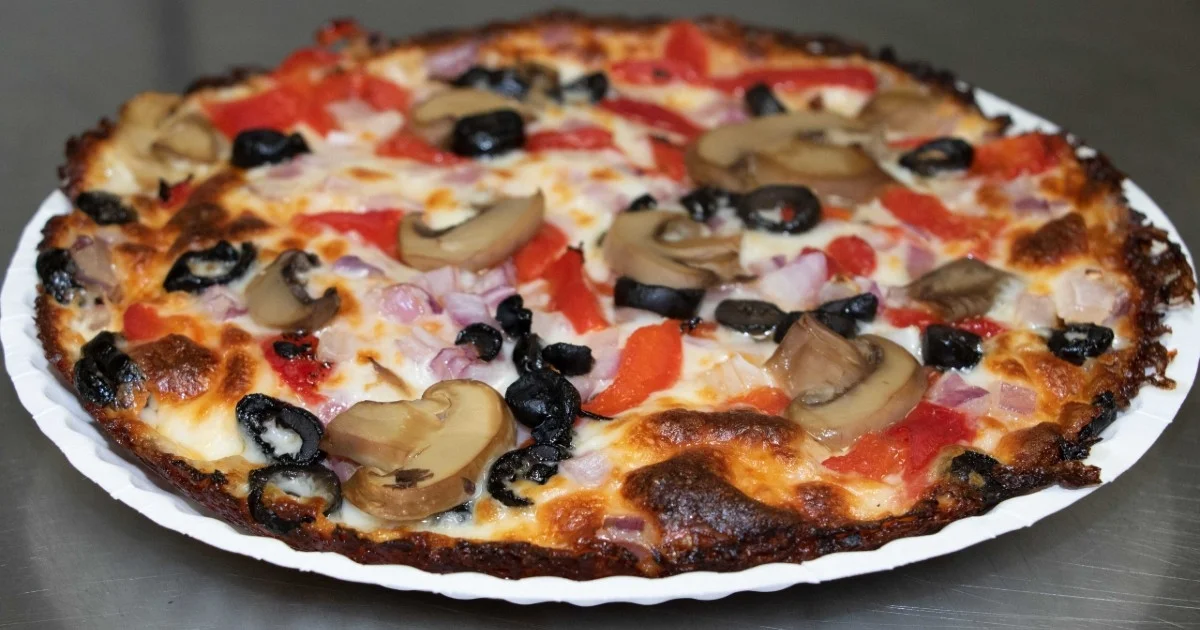 A pizza loaded with a variety of toppings including mushrooms, olives, and red peppers on a golden crust.
