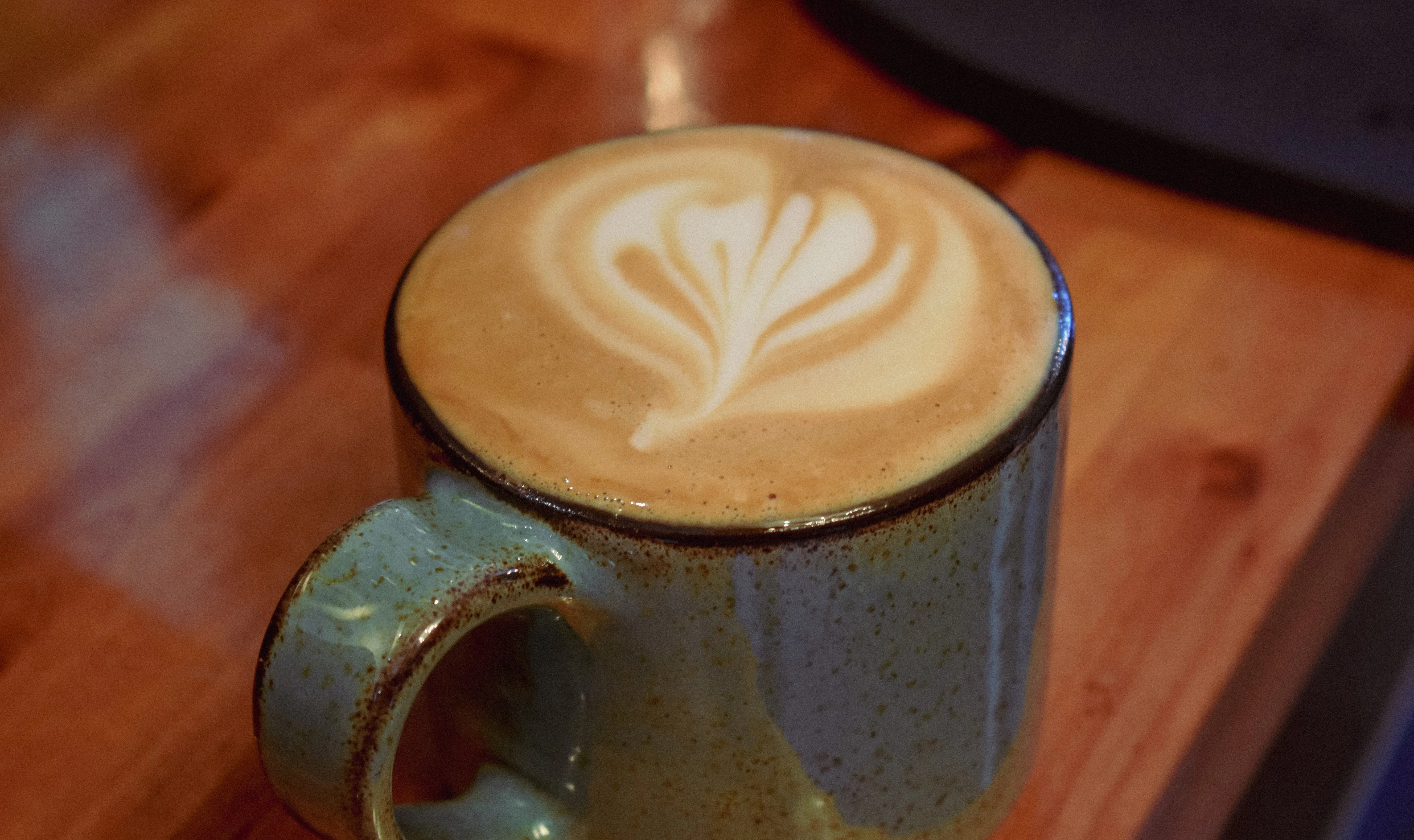 Cup of coffee with frothy milk on a wooden table