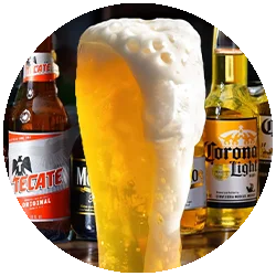 Chilled beer glass with frothy head and assorted beer bottles in the background