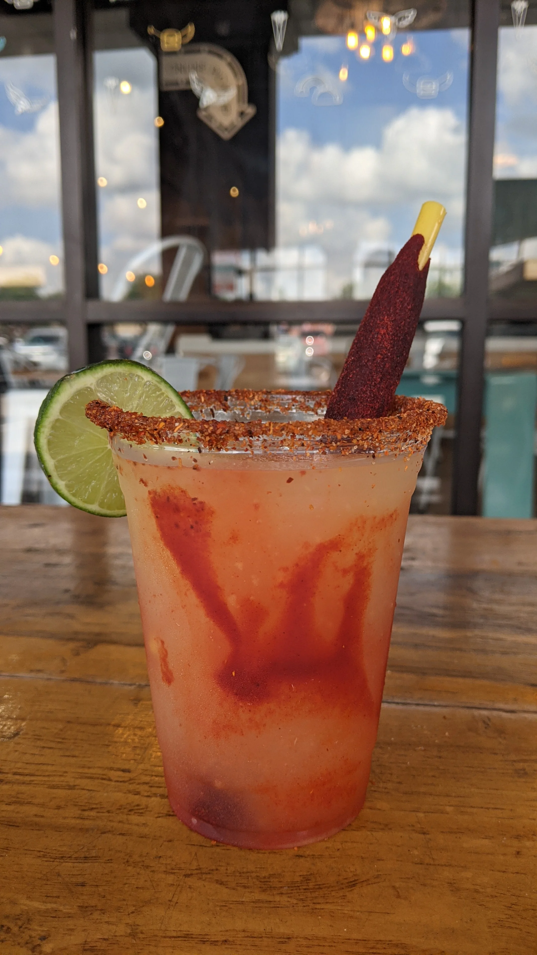 Colorful Mexican michelada cocktail with lime and tamarind stick