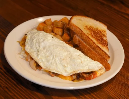 Omelet with toast and diced potatoes on a white plate