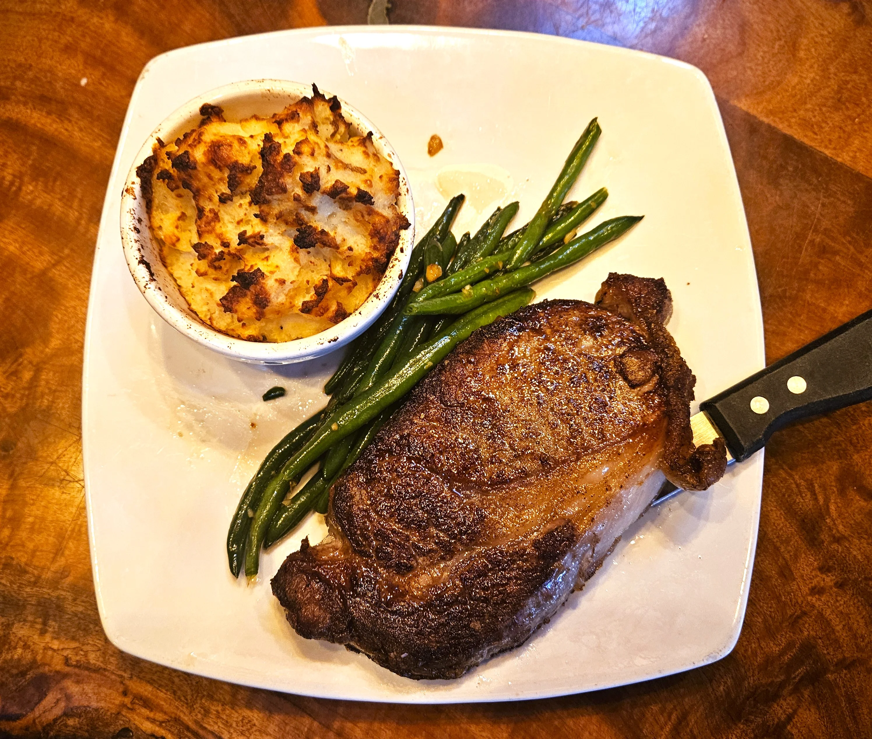 Grilled ribeye steak with green beans and creamy potato casserole