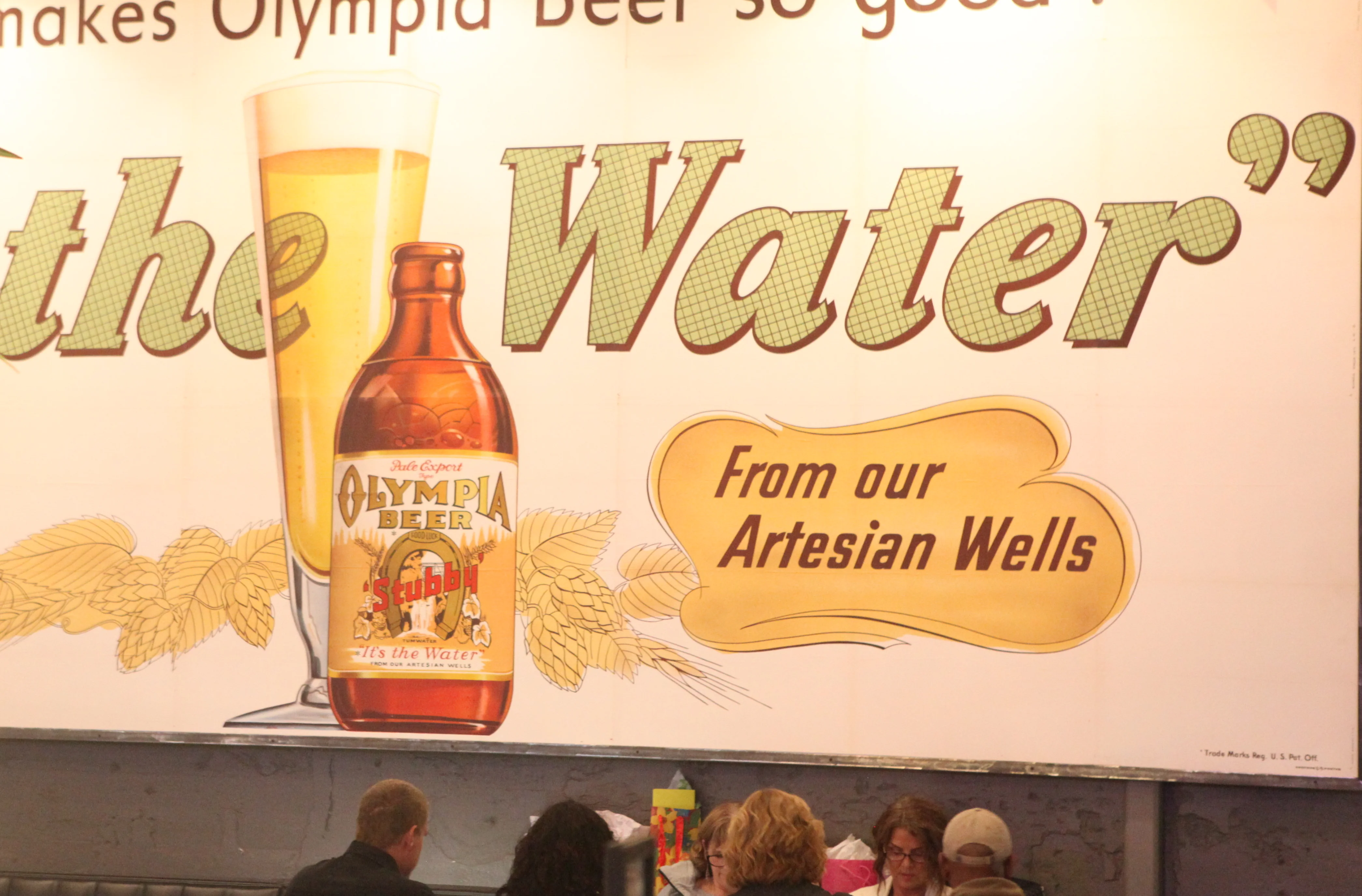 Vintage Olympia Beer advertisement in a cozy restaurant setting