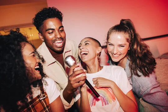 Group of friends enjoying karaoke together, laughing and singing.