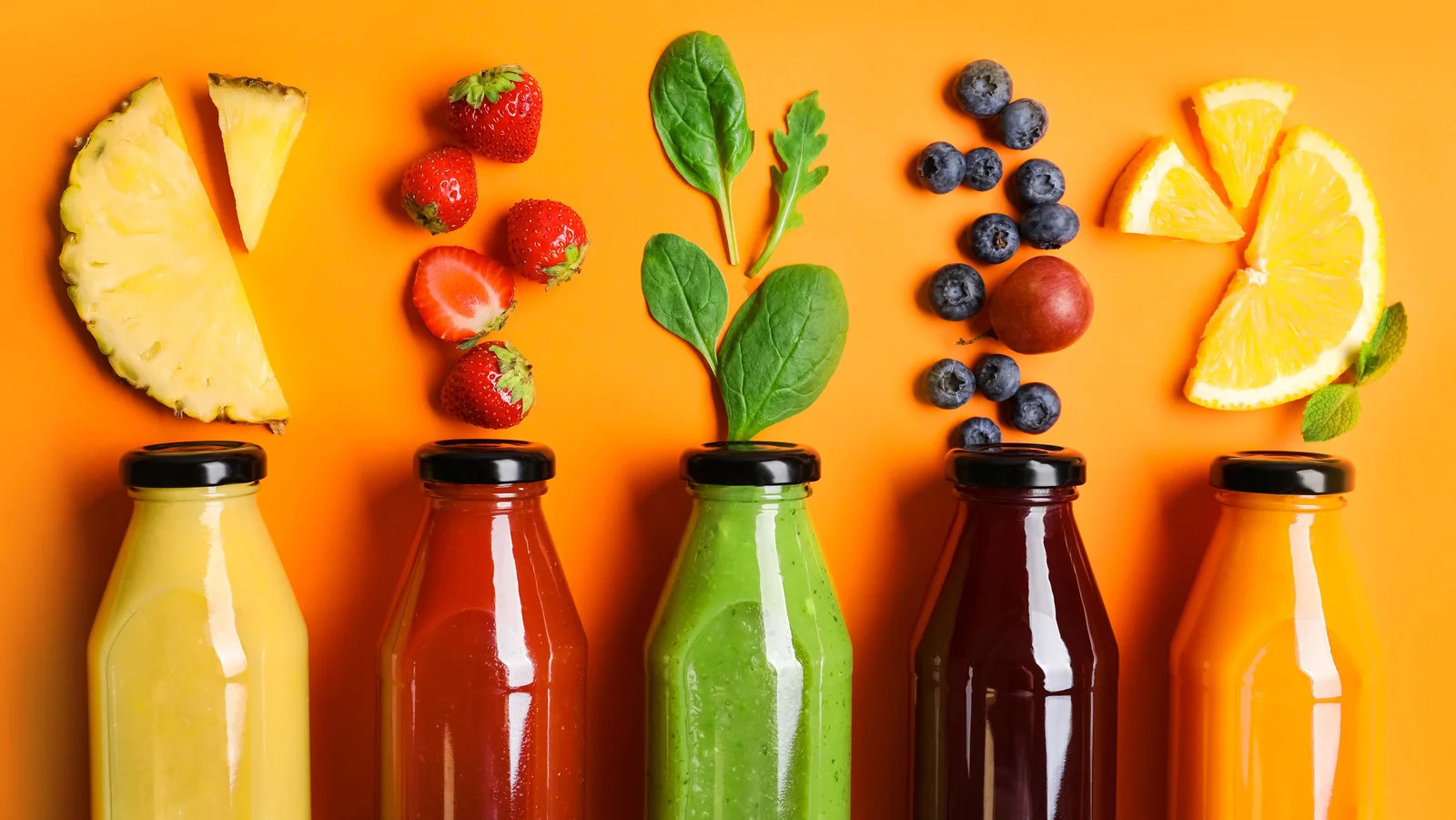 Colorful assortment of fresh juices and fruits on a vibrant background
