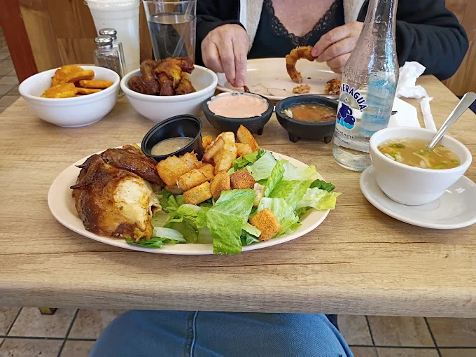 A plate of grilled chicken, salad, and sides at a restaurant table.