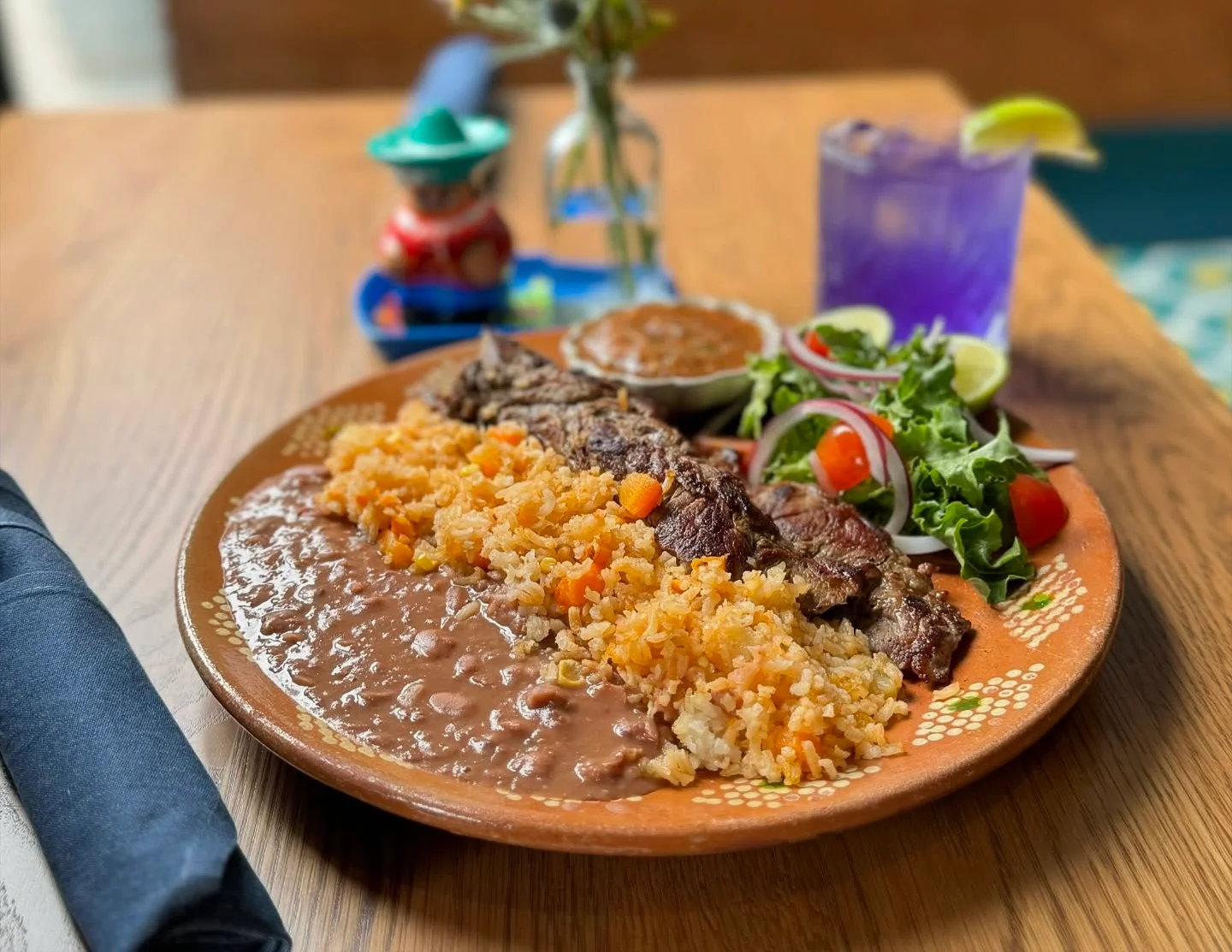 Grilled carne asada with rice and beans in a vibrant Mexican setting