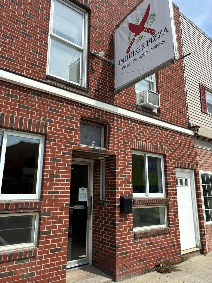 Exterior view of Indulge Pizza restaurant with brick facade