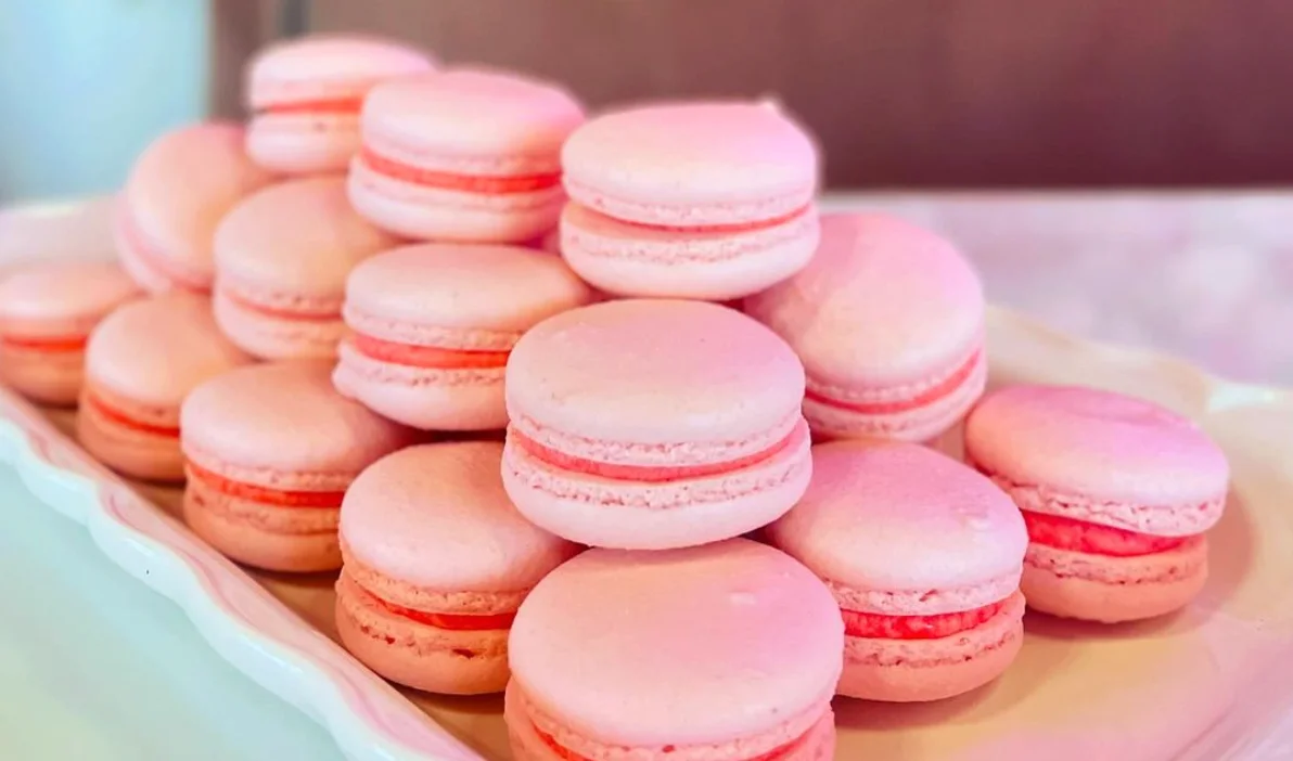 Delicate pink French macarons stacked on a white platter