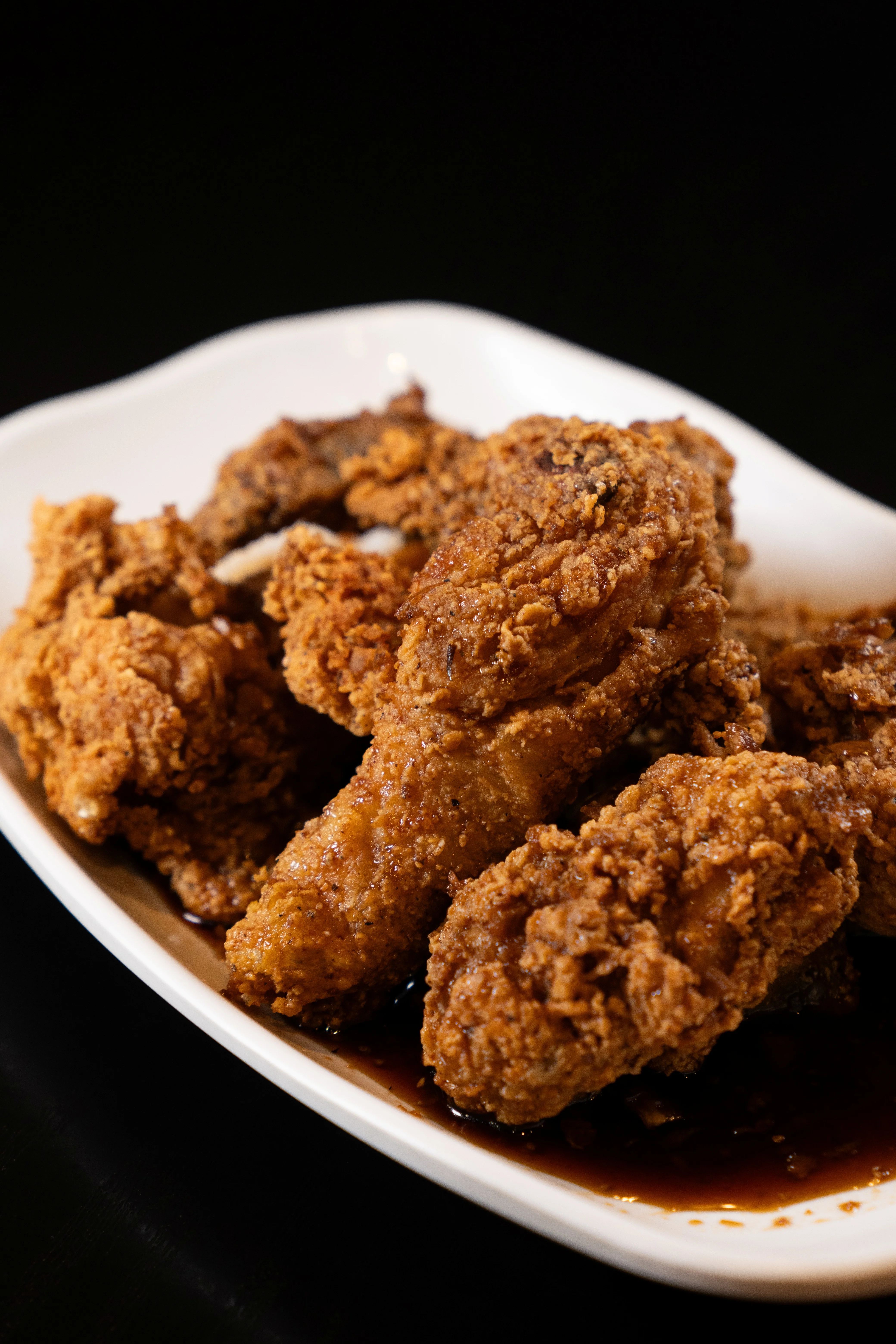 Plate of crispy fried chicken wings on a dark background.