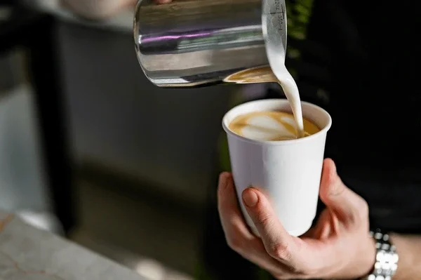 Barista pouring latte art into a coffee cup