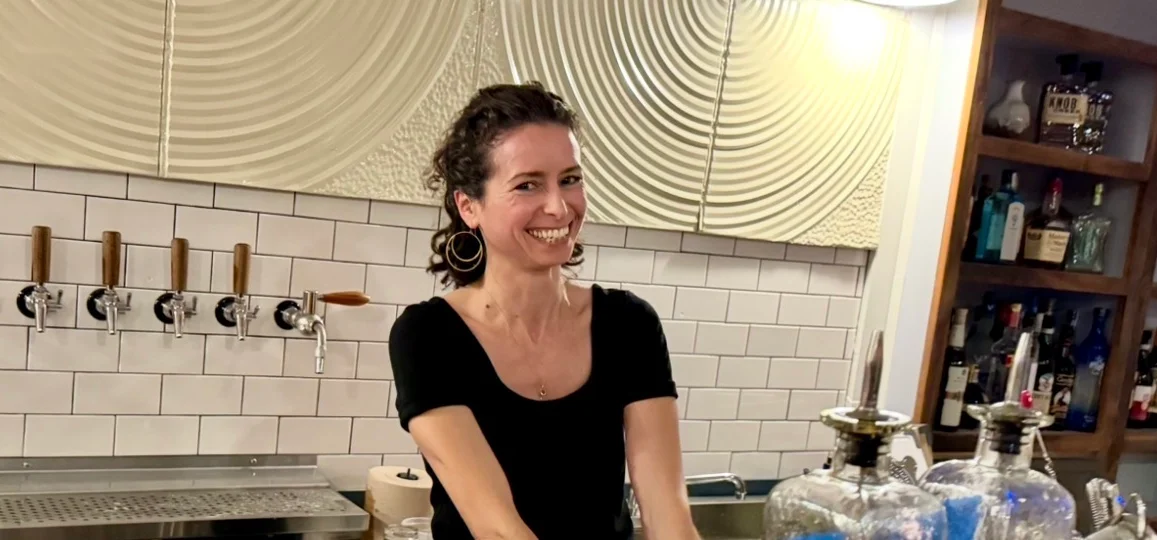 Bartender smiling while mixing cocktails at a stylish bar