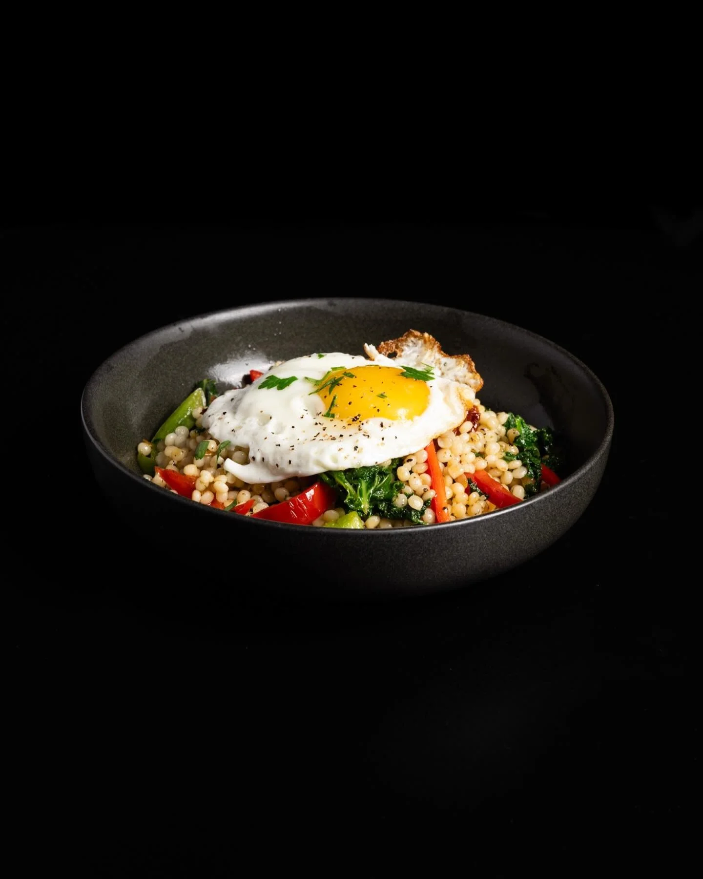 Mediterranean couscous bowl topped with a fried egg