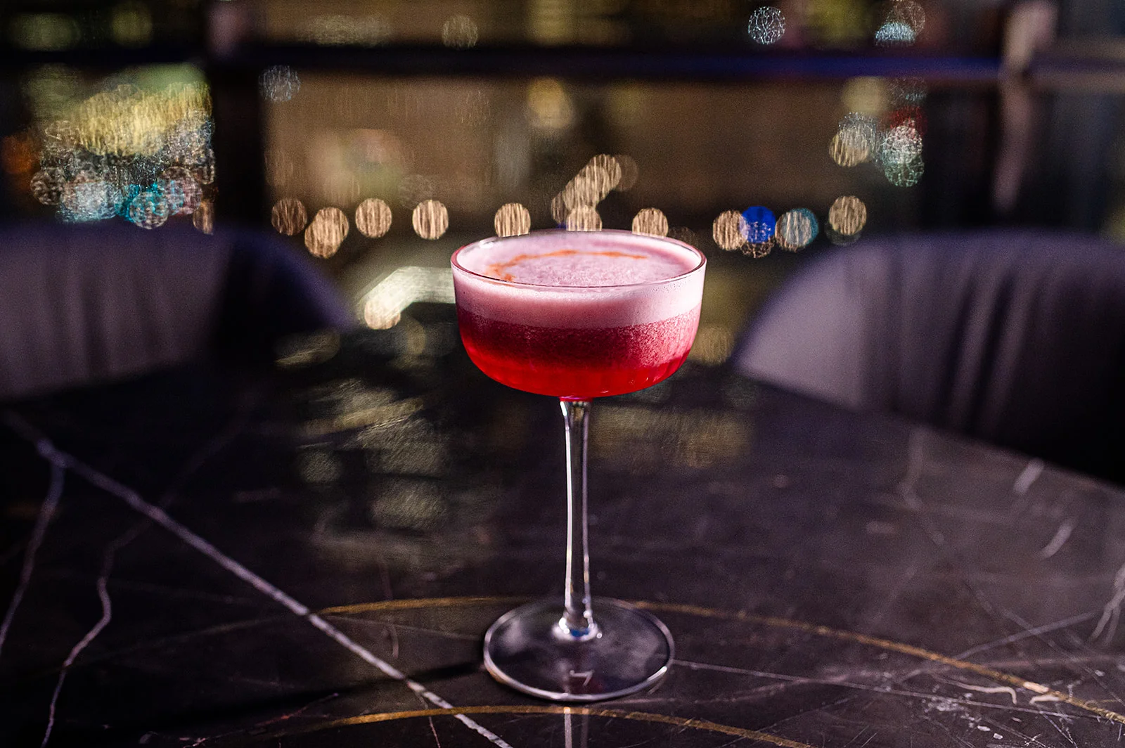 Elegant cocktail with a vibrant red hue against a city skyline
