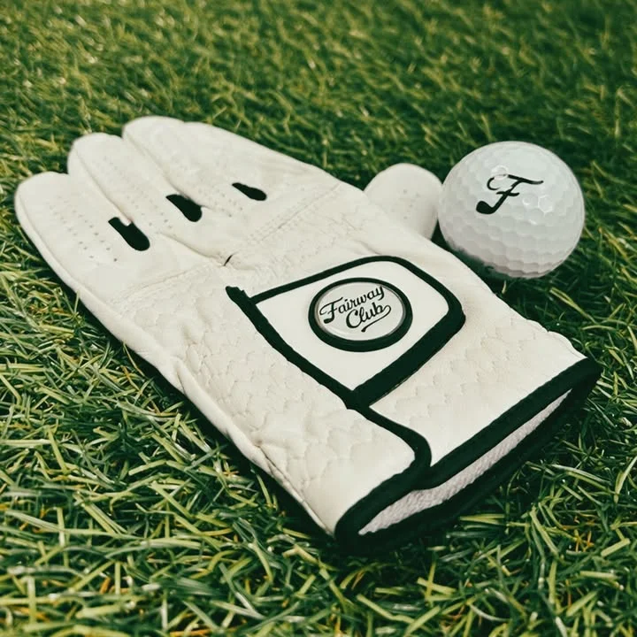 A white golf glove and a golf ball on green grass.