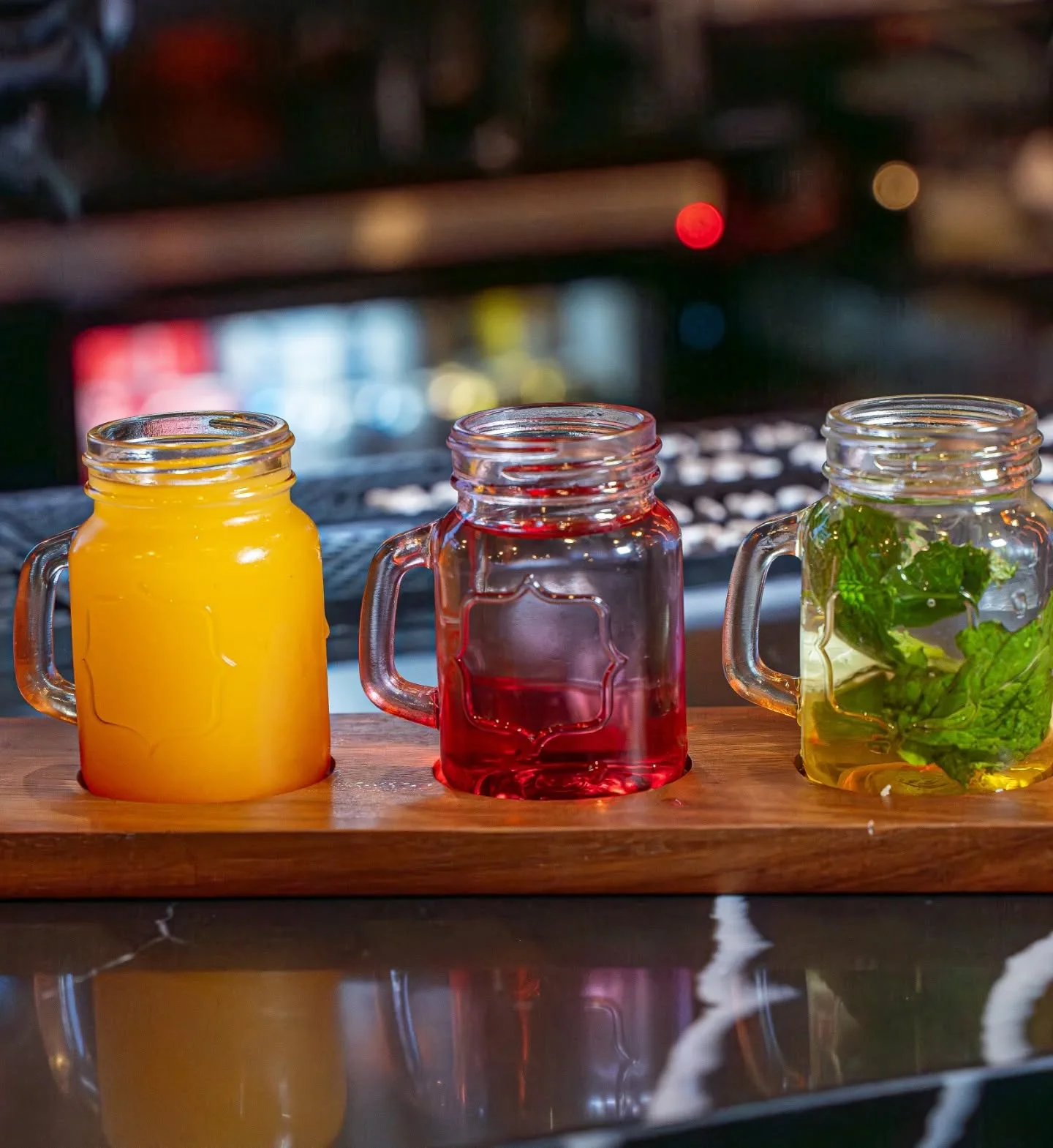 Colorful mocktail flight in mason jars on a wooden tray