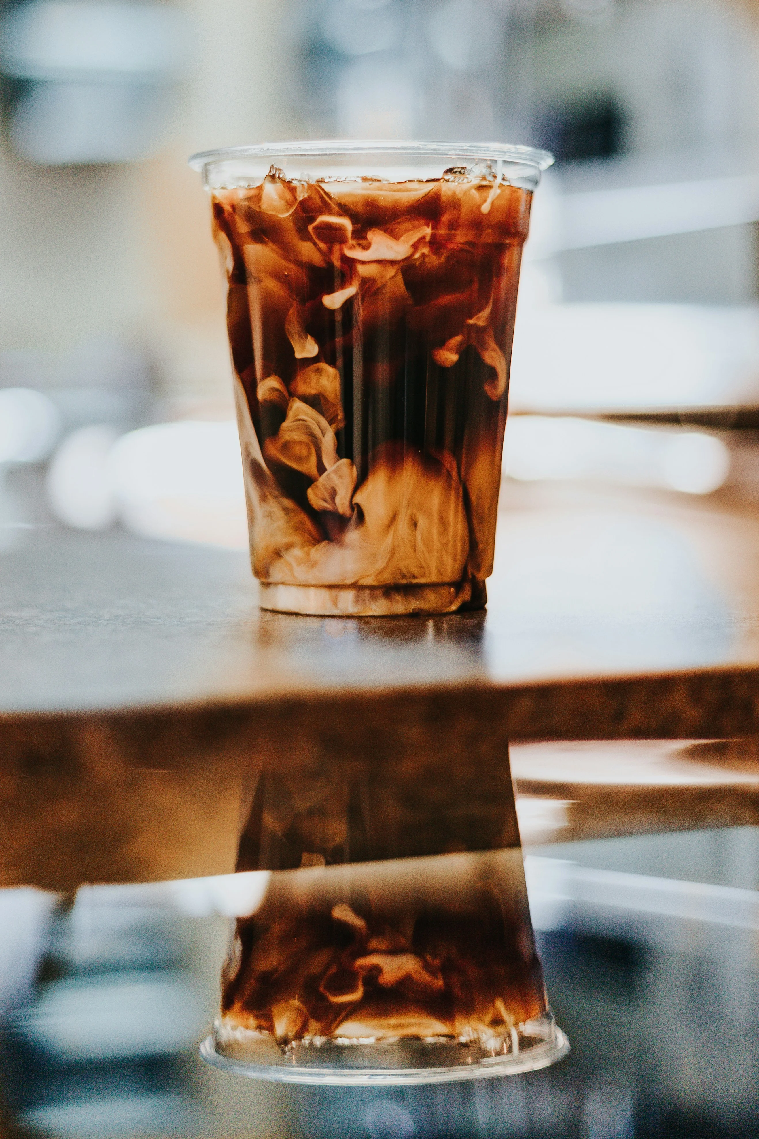 Iced coffee with cream swirling in a clear cup