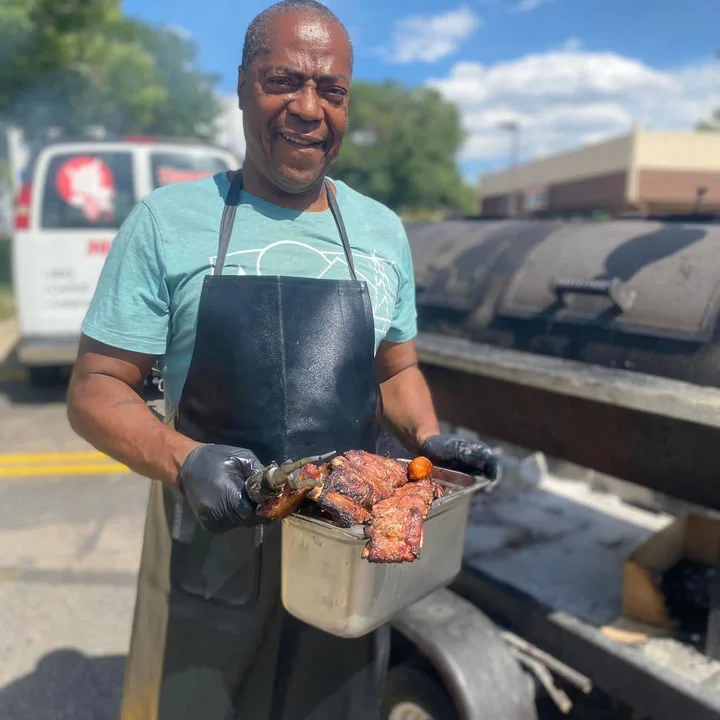 Grilled barbecue ribs served outdoors by a smiling chef