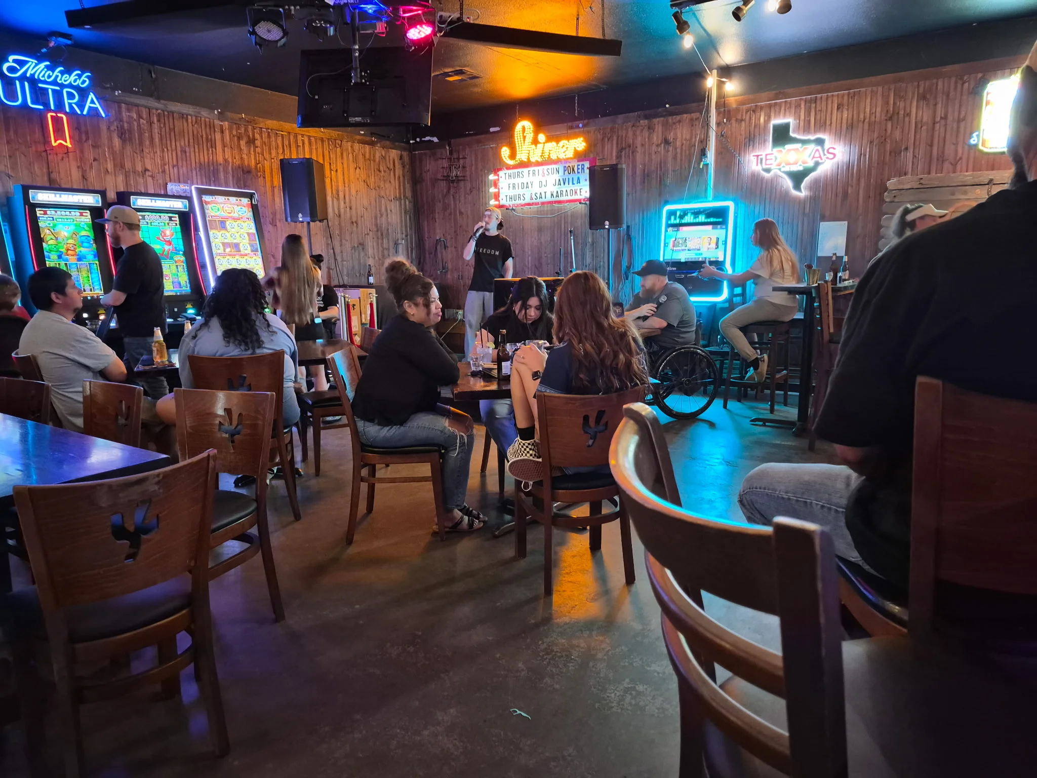 Lively bar scene with patrons enjoying drinks and entertainment in a rustic setting
