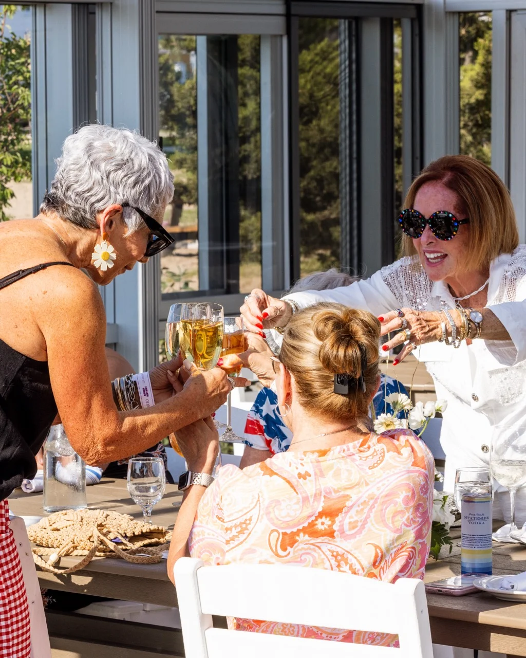Friends toasting with drinks at a sunny outdoor gathering