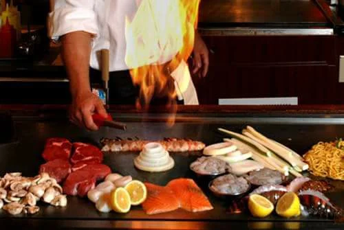Japanese teppanyaki chef grilling seafood and steak