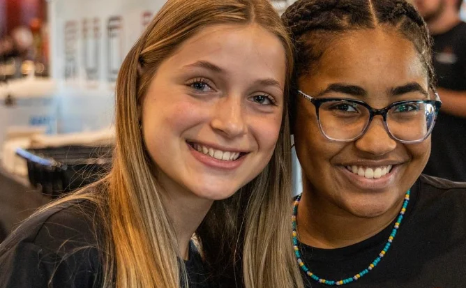 Two smiling staff members at a lively restaurant