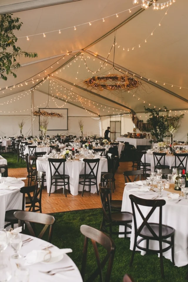 Elegant dining setup in a tent with string lights and floral decor