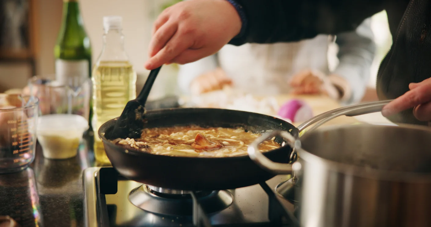 Cooking risotto in a skillet with a wooden spoon