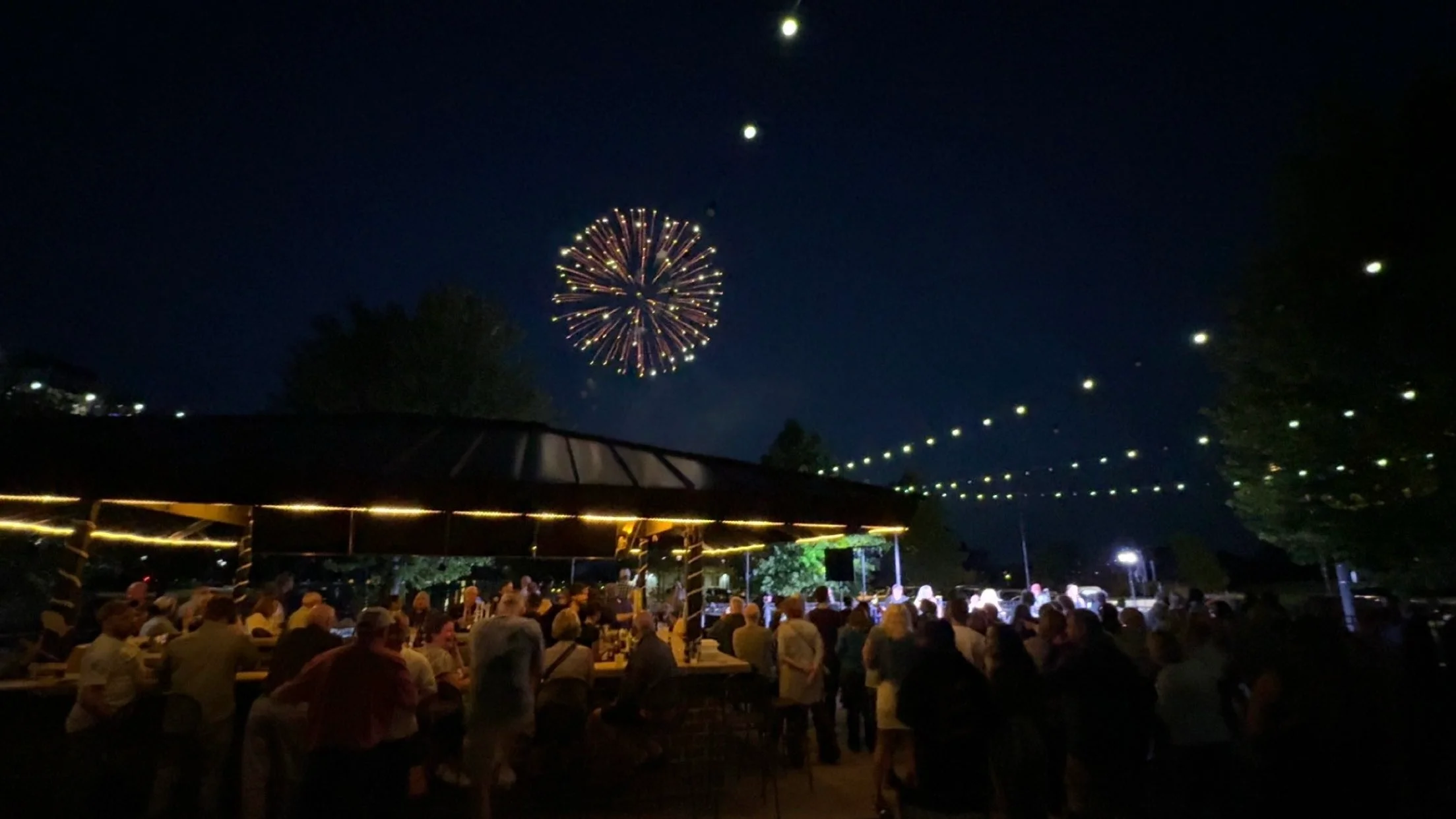Outdoor dining area with string lights and lively atmosphere at night