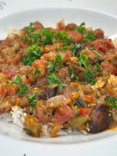 A bowl of rice topped with a flavorful mixture of shrimp, vegetables, and herbs.