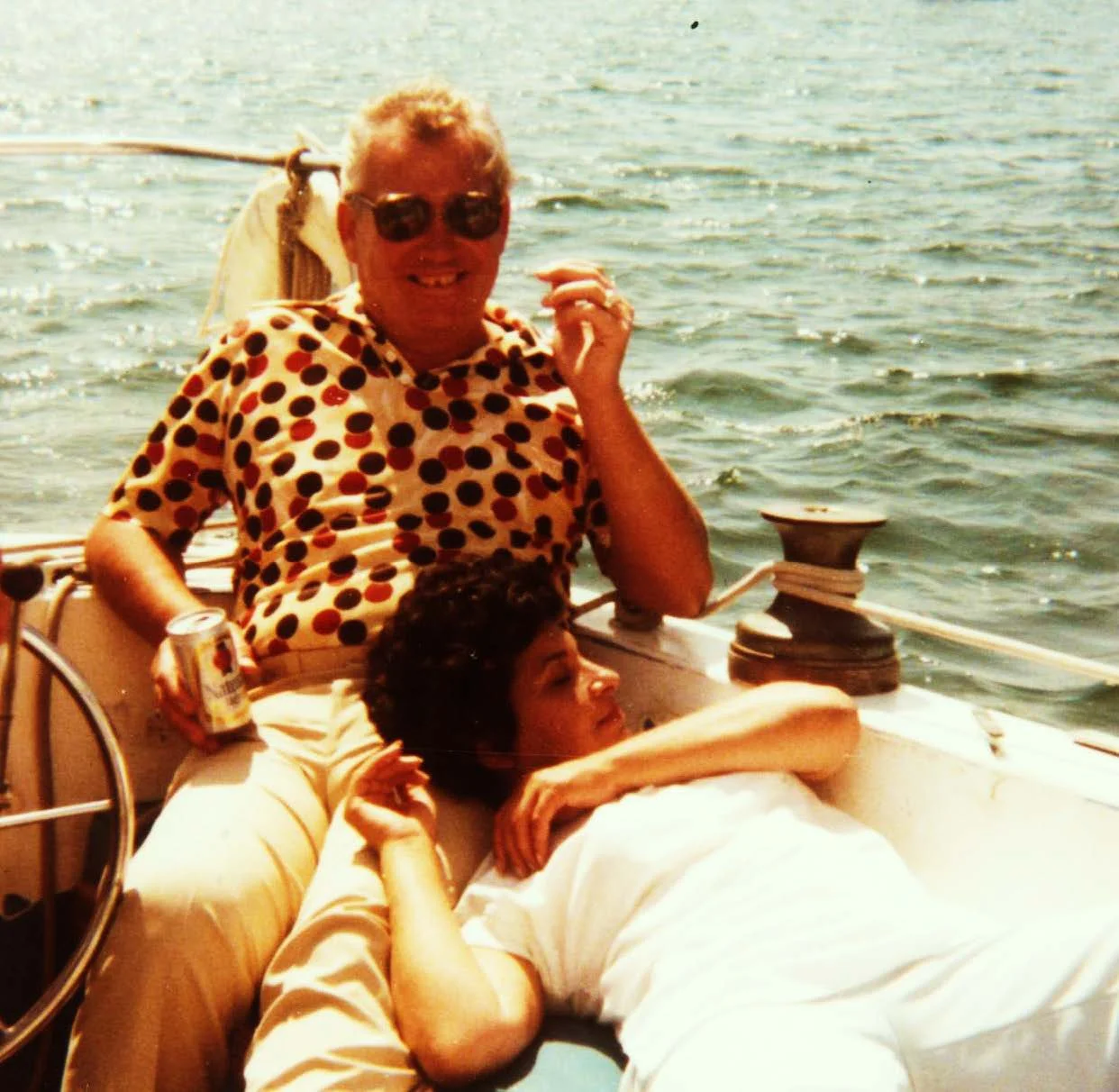 Couple relaxing on a sailboat by the water