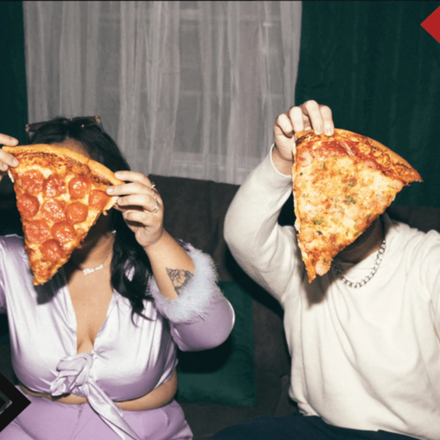 Two people holding large slices of pepperoni pizza