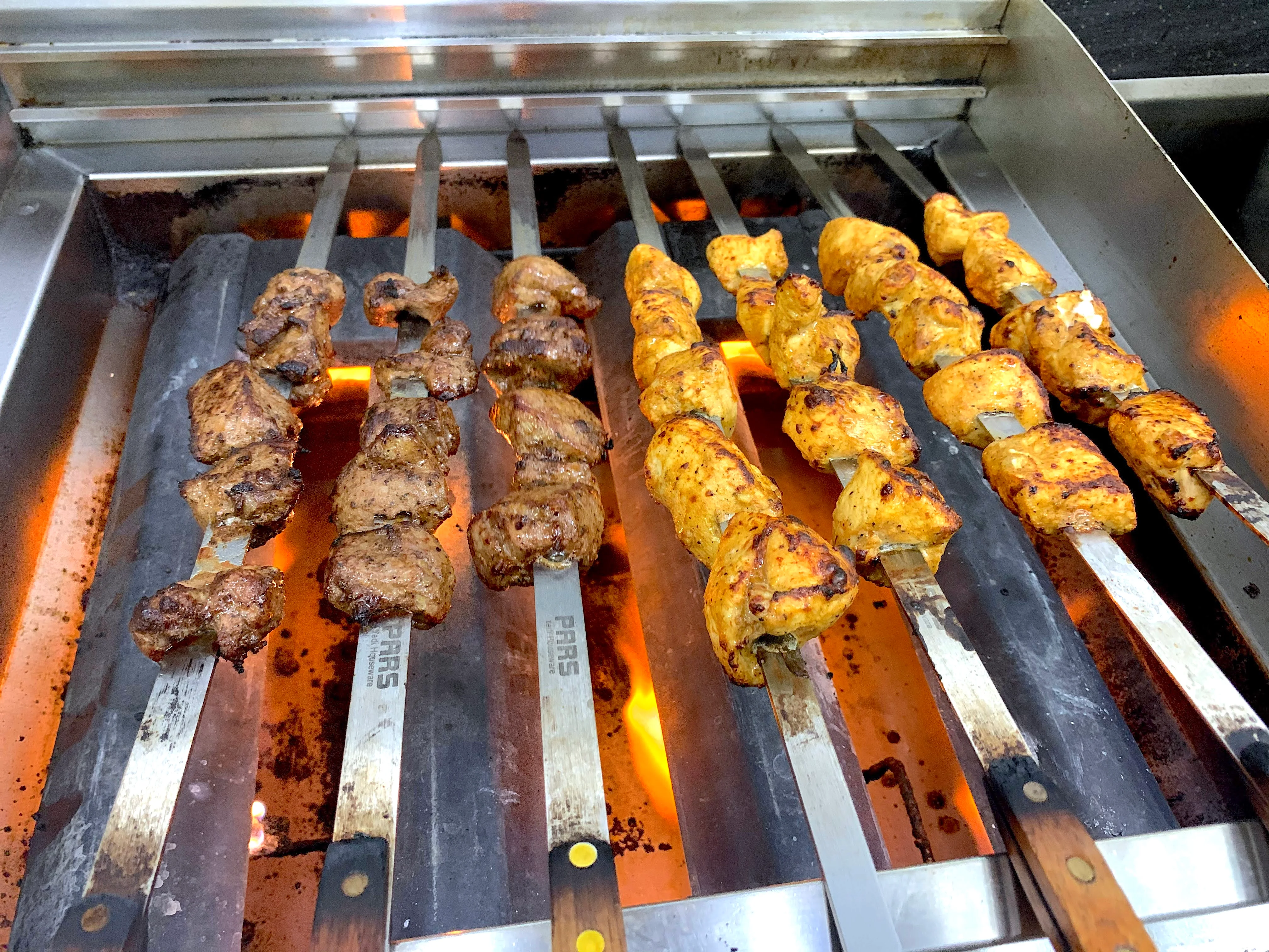 Grilled kebabs on skewers over open flame