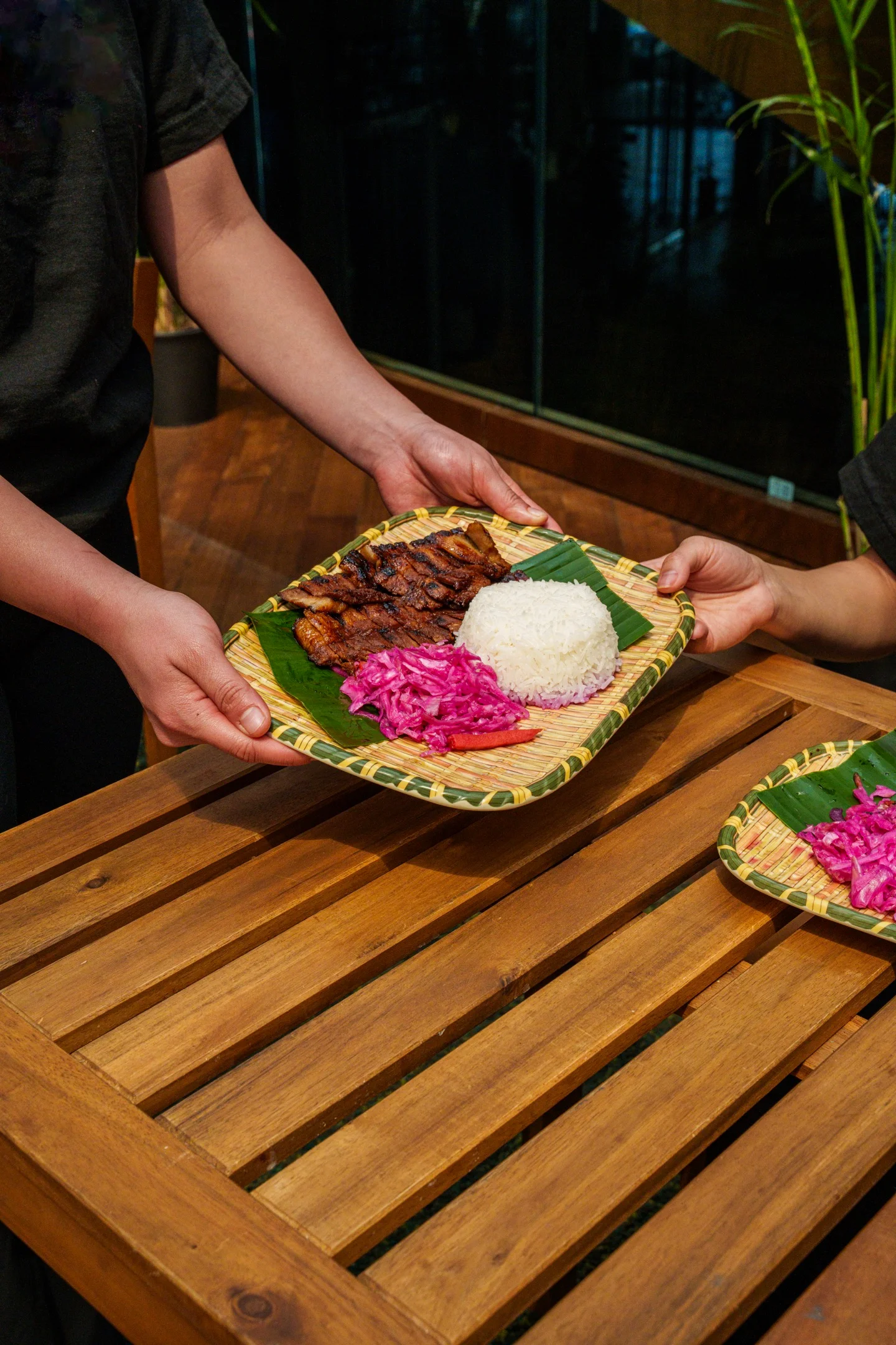 Grilled chicken served with rice and pickled vegetables in a tropical setting