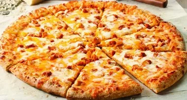 A whole pizza with a golden crust, topped with cheese and chunks of chicken, cut into eight slices.