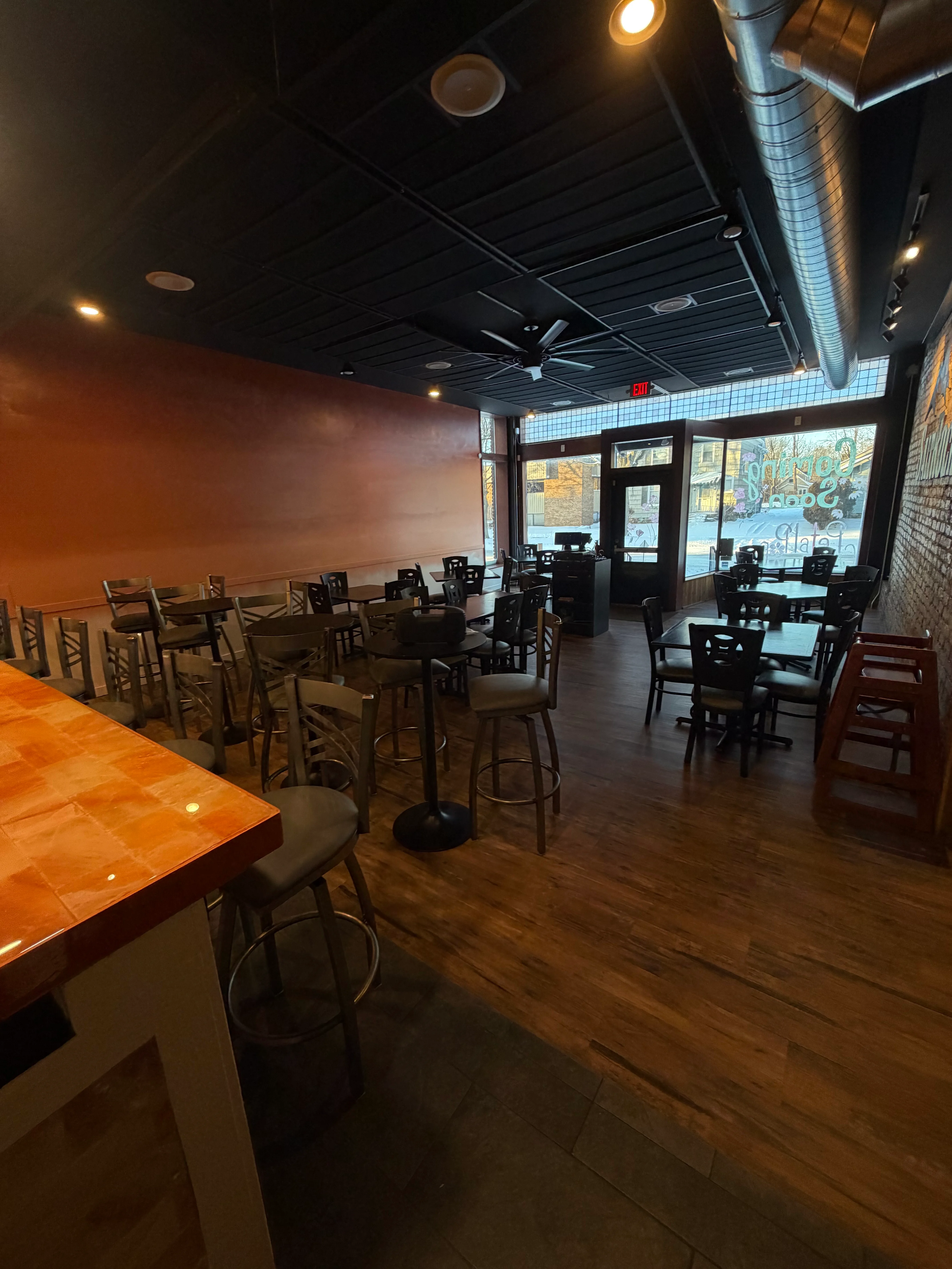 An empty indoor restaurant space with wooden floors, tables, and chairs, showcasing a welcoming ambiance.