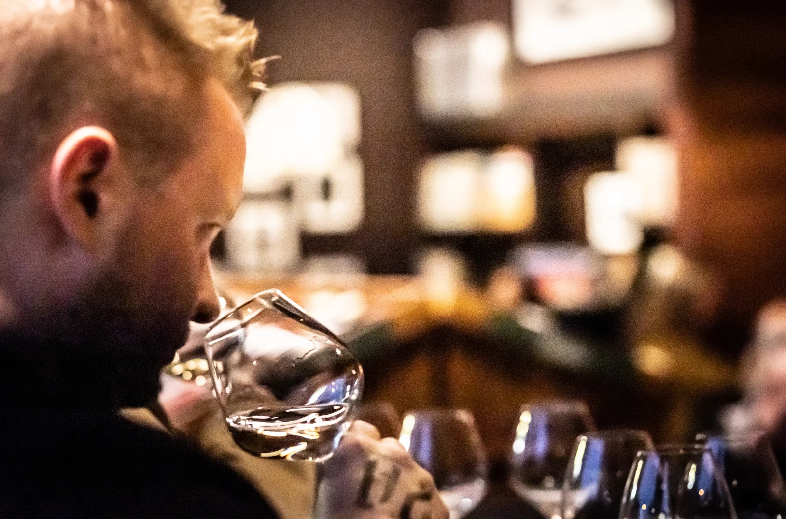 Bartender examining a glass of spirits in a stylish bar setting