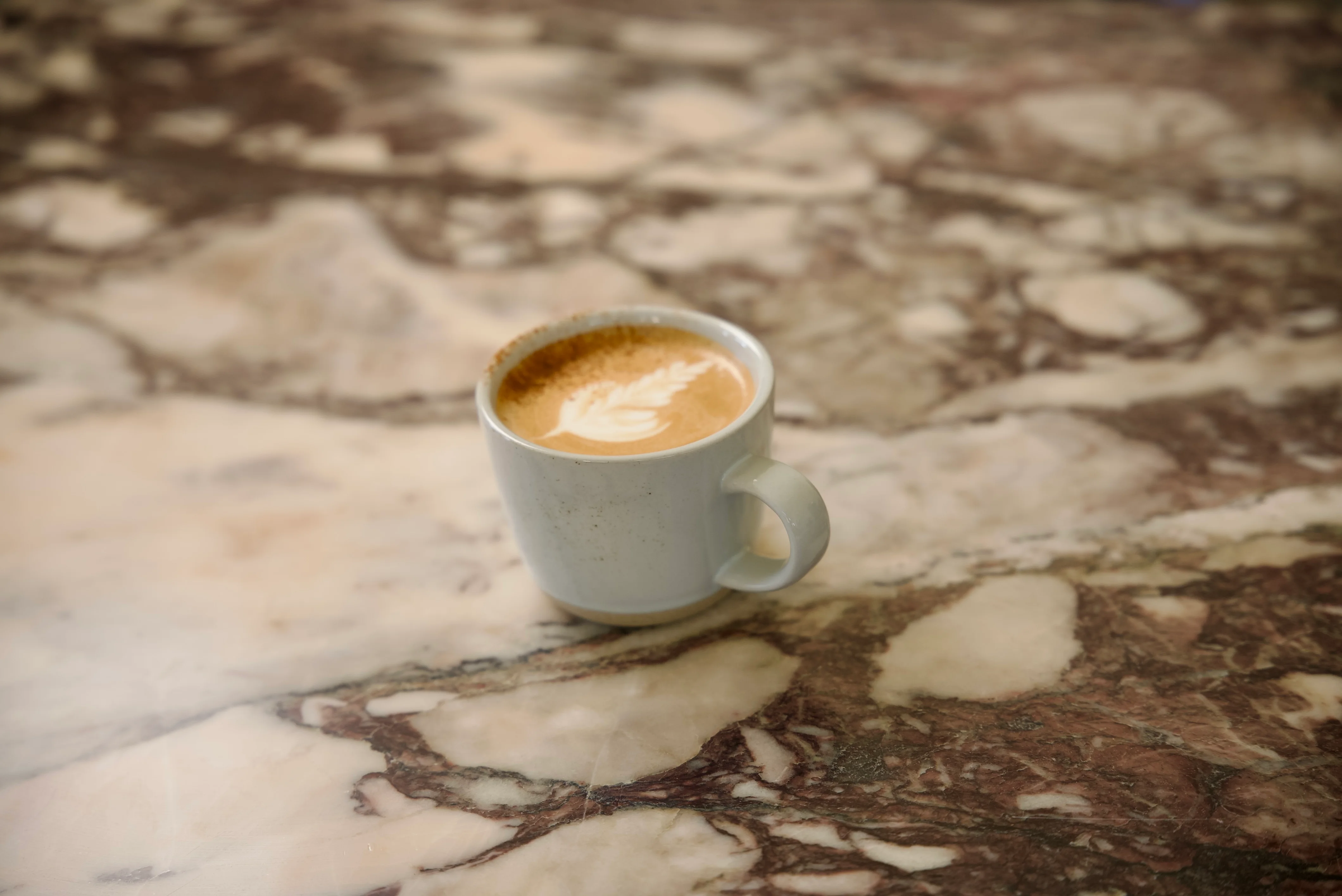Artisan latte with leaf design on marble table